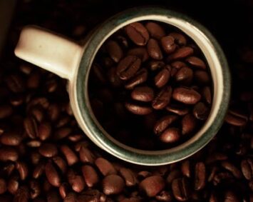 Overhead view of coffee beans filling a mug, perfect for coffee lovers and cafes.