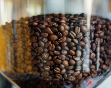 Aromatic roasted coffee beans stored in a clear glass jar, showcasing rich textures.