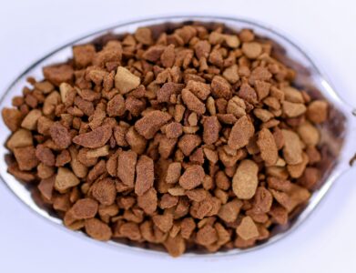Detailed close-up view of instant coffee granules on a metal spoon, highlighting texture and color.