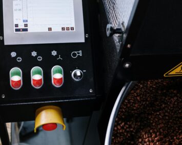 Close-up of a coffee roasting machine with a digital control panel and freshly roasted beans.