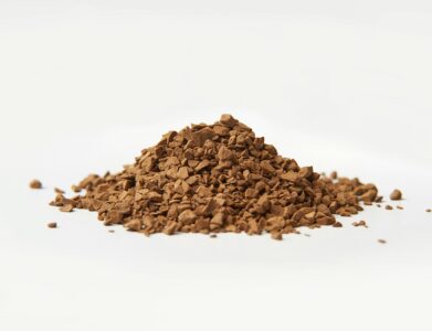 A close-up image of brown instant coffee granules on a white background.