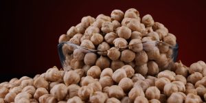 Glass cup with chickpeas on a beautiful illuminated red background.