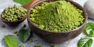 Matcha powder in a wooden bowl with a wooden spoon, surrounded by fresh green leaves. the vibrant green tone highlights its natural, organic nature, perfect for culinary, wellness, or holistic themes. Generative AI